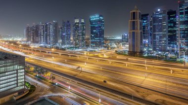 Jumeirah lakes havadan görünümü ile ışıklandırılmış gökdelenler gece timelapse Şeyh zayed road ve metro hattı üzerinde trafik ile kuleleri. Dubai Yat Limanı çatı görünümü