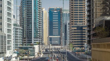 Dubai Marina 'da gökdelenler zaman çizelgesi ve kanaldan geçen beton yol köprüsü yakınındaki trafik tramvayları var. Dubai, Birleşik Arap Emirlikleri.