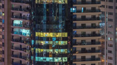 Windows çok katlı binanın içinde aydınlatma ve insanlar timelapse içinde hareketli çelik ve cam. Modern konut ve ofis gökdelenler Dubai Marina havadan görünümü