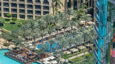 Dubai şehir merkezi zaman çizelgesi, lüks modern binalar ve palmiyelerle çevrili yüzme havuzu, Birleşik Arap Emirlikleri 'nin gelecekteki şehirleri. Gökdelenden gökyüzü görüntüsü