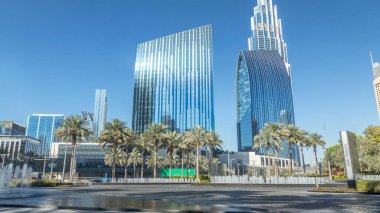 Çeşmeler en yüksek gökdelen timelapse, Dubai ana girişe yakın. Palmiye ve arka plan üzerinde modern kuleli güneşli gün, downtown Dubai yolda trafik