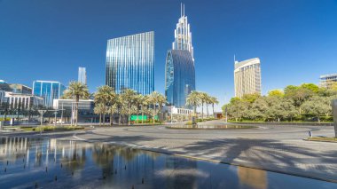 Çeşmeler en yüksek gökdelen timelapse hyperlapse, Dubai ana girişe yakın. Palmiye ve arka plan üzerinde modern kuleli güneşli gün, downtown Dubai yolda trafik