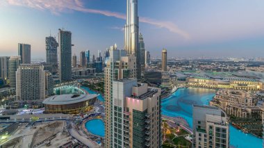 Dubai şehir merkezinden geceye geçiş, fıskiyeli lüks modern binalar, Birleşik Arap Emirlikleri 'nin renkli fütüristik şehirleri. Gün batımından sonra gökdelenden gökyüzü görüntüsü