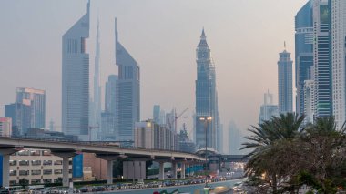 Şeyh Zayed Yolu 'ndaki kavşak ve köprüde trafik. Etrafı finans bölgesinin gökdelenleriyle çevrili. Akşam Dubai 'deki Birleşik Arap Emirlikleri' nin yukarıdan görüntüsü