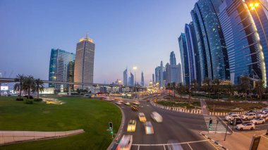 Şeyh Zayed Yolu 'ndaki kavşak ve köprüde trafik gece gündüz gökdelenlerle çevrili geçiş zamanı panoramasıyla. Akşam Dubai 'deki Birleşik Arap Emirlikleri' nin yukarıdan görüntüsü