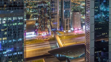 Sheikh Zayed Road ve DIFC gece timelapse Dubai, BAE binaların görünümünü manzarası. Finans merkezi metro istasyonu ile yukarıdan havadan görünümü içinde ışıklandırılmış gökdelenler