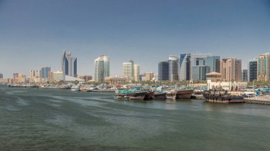 Trading wooden boats in the port timelapse. Merchant ships on the Creek Canal. Skyscrapers on background. Panoramic view form bridge clipart