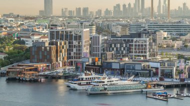 Dubai creek manzara timelapse tekneler ve yatlar ve gün batımı sırasında arka planda şehir gökdelenler ile modern binalar ile. Yukarıdan hava üstten görünüm