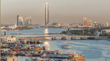 Dubai creek manzara timelapse tekneler ve bağlantı noktası, sakin su ve gün batımı sırasında arka planda modern binalar gemi ile. Gökdelen yansıyan güneş ile yukarıdan hava üstten görünüm