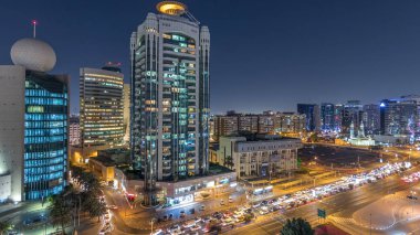 Dubai Creek bölgesi modern binalar ve kalabalık trafik sokağı gece panoramasıyla çevrili. Aydınlatılmış gökdelenlerle yukarıdan gökyüzü görüntüsü