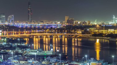 Dubai creek manzara gece timelapse tekneler ve yatlar ve modern binalar köprüde trafik ile. Yukarıdan hava üstten görünüm