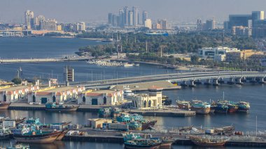 Dubai deresi manzarası, park zamanları, limanda tekneler ve gemiler, günbatımında sakin sular ve modern binalar. Yukarıdan hava üstü görünümü