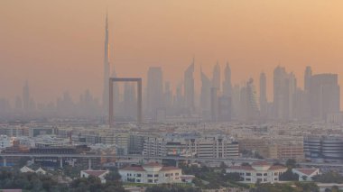 Dubai deresi manzarası günden geceye geçiş zamanı aydınlatılmış modern binalar ve şehir merkezindeki gökdelenler ve gökdelenler. Yukarıdan hava üstü görünümü