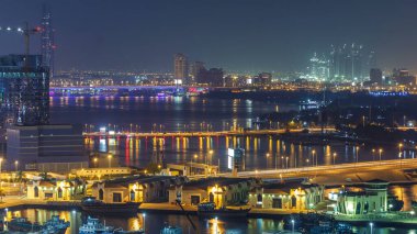 Dubai deresi gece manzarası limanda tekneler ve yatlar ve köprüde trafik olan modern binalar. İnşaat alanı yukarıdan gökyüzü görüntüsü