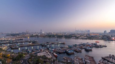 Dubai Deresi manzara panoraması günden geceye geçiş zamanı tekneler, yatlar ve yollarda trafiği olan modern binalar. Yukarıdan hava üstü görünümü