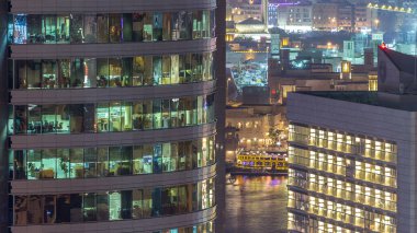 Windows çok katlı binanın içinde aydınlatma ve insanlar timelapse içinde hareketli çelik ve cam. Dubai deira modern ofis gökdelenlerin havadan görünümü. Su Creek arka plan üzerinde