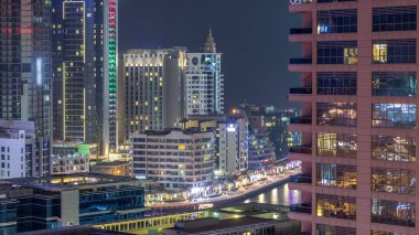 Dubai Marina havadan görünümden bir noktadan gece timelapse. Waterfront adlı mesire üzerinde yürüyen insanlar. Modern gökdelenler ve konut kuleleri parlayan pencerelerle aydınlatılmış