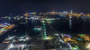 Palm Jumeirah Adası 'nın gece görüntüsü. Işıklı villaları, otelleri ve yatları olan en iyi panoramik manzara. Yeni gemi terminalinin inşa süreci