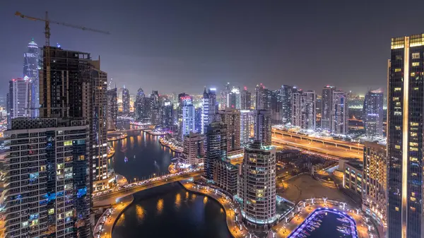 Dubai Yat limanı manzarası, gece timelapse üzerinde su kanalı. Konut kuleleri aydınlatma ve aydınlatma ile. Yat ve tekne trafiği olan gökdelenler yüzen