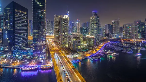 Water canal on Dubai Marina skyline at night timelapse. Residential towers with lighting and illumination. Floating yachts and boats with traffic near skyscrapers