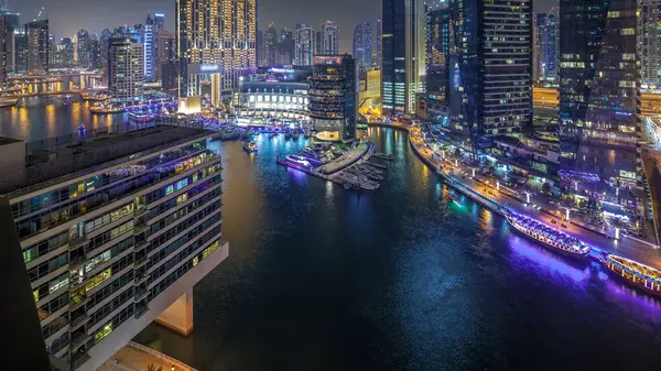 Water canal on Dubai Marina panoramic skyline at night timelapse. Residential towers with lighting and illumination. Floating yachts and boats with traffic near skyscrapers