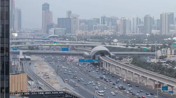 Jumeirah göl kulelerinin, gökdelenlerin ve Al Barsha bölgesinin gece gündüz geçiş zamanının havadan görüntüsü. Golf sahası ve metro hattı yakınlarındaki Şeyh Zized yolunda trafik var..