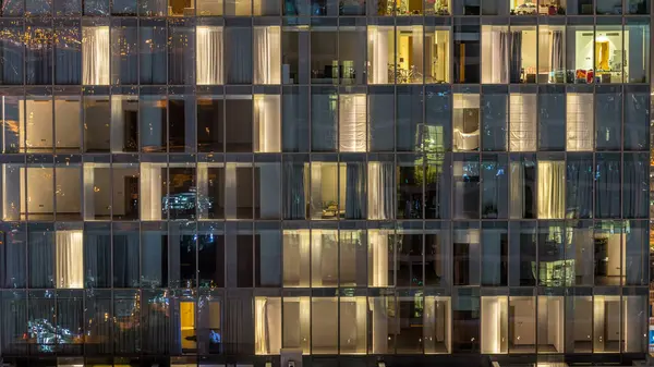 点滅し ガラスとスチールの内部照明とタイムラプス内の人の移動の多階建ての建物の窓を点滅します ドバイのダウンタウンのモダンな住宅高層ビルの空撮 — ストック写真
