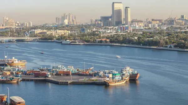 Dubai deresi zaman çizelgesi, limanda tekne ve gemi, sakin su ve günbatımında modern binalar. Yukarıdan iskelenin havadan görünümü
