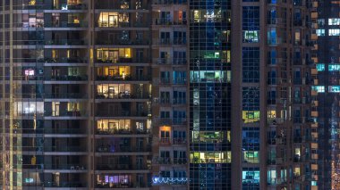 Çok öykülü modern cam konut içinde parlayan pencere eşiği ışık gece timelapse bina. Daireler insanlar. Evler de akşam aydınlatılmış. Dubai Marina, Birleşik Arap Emirlikleri.