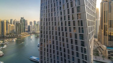 Dubai Marina gezinti alanı ve kanalı, gün batımından önce Dubai, BAE 'de yüzen yatlar ve teknelerle güzel bir hava manzarası. Akşam saatlerinde pencereli modern kuleler ve gökdelenler