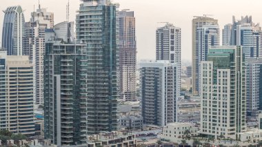 Lüks Dubai Marina Kanalı 'ndan geçen tekneler ve gece gündüz restoranlarla gezinti günbatımından sonra aydınlık gökdelenlerle yukarıdan manzaralı. Dubai, Birleşik Arap Emirlikleri