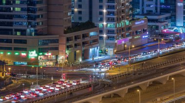 Bir büyük şehir gece timelapse bir yol kavşak hava görünümünü. Arabalar ve tramvay ile UAE Dubai Yat Limanı bölgesinin kentsel peyzaj