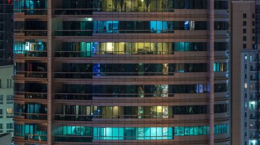 Çok öykülü modern cam konut içinde parlayan pencere eşiği ışık gece timelapse bina. Daireler insanlar. Akşam aydınlatılmış gökdelenler. Dubai Marina, Birleşik Arap Emirlikleri.