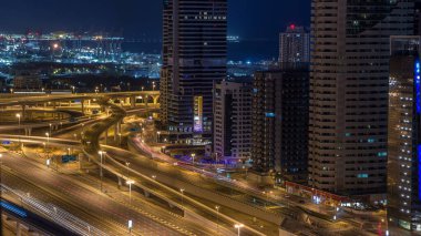 Dubai Yat Limanı gökdelenler hava üstten görünüm güneş doğmadan önce Jlt gelen Dubai gece gün timelapse, Birleşik Arap Emirlikleri için. Işıklı modern kuleleri ve kavşak ile Şeyh zayed yolu üzerinde trafik