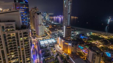 Modern ışıklandırılmış gökdelenler ve Jumeirah Beach Residence (Jbr) gece timelapse Dubai, BAE kumsalda hava görünümünü. Tekneler ve yatlar Körfezi'nin su üzerinde yüzen