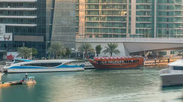 Yat ve tekne shoping mall kalıyor ve Dubai Marina bölge timelapse bir köprü altında geçen turist. Akşam gün batımı sırasında hava üstten görünüm.