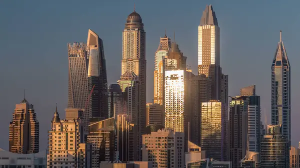 Dubai Yat Limanı günbatımı hava timelapse sırasında Birleşik Arap Emirlikleri kuleleri. Güneş gökdelenler uzun gölgeler ile yansıyan. Yolda trafik ile Jlt üzerinden üstten görünüm