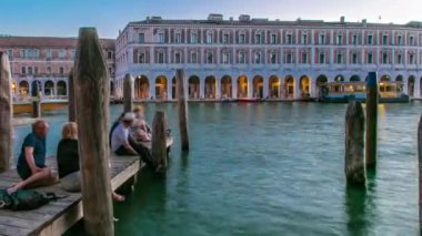 Gün batımından sonra Rialto Pazarı 'na geçiş süresini izleyin. San Polo, Venedik, İtalya Büyük Kanal' ın karşısında oturan insanlar ve botlarla iskeleden izlendi.
