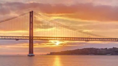 Lisbon city sunrise with April 25 bridge timelapse, River and waterfront early morning. Orange clouds on the sky