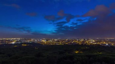 Panoramic dawn view over Lisbon and Almada from a viewpoint in Monsanto night to day transition timelapse. Aerial top overview with traffic on city streets