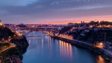 Günbegün Portekiz 'in tarihi Porto şehrinin havadan görüntüsü Dom Luiz köprüsü ile panoramik zaman dilimi. Aydınlatılmış kıyı şeridi yukarıdan nehre yansıyor
