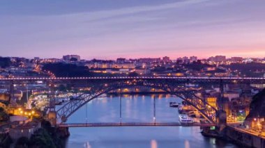 Day to night transition aerial close up view of the historic city of Porto, Portugal timelapse with the Dom Luiz bridge. Illuminated waterfront and curved river from above
