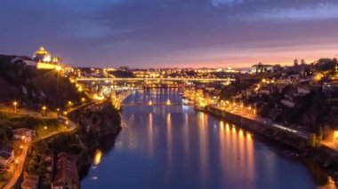 Day to night transition aerial view of the historic city of Porto, Portugal timelapse panorama with the Dom Luiz bridge. Illuminated waterfront and curved river from above