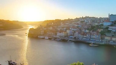 Panorama of old city Porto at river Duoro, with Port transporting boats at sunset timelapse with the Dom Luiz bridge, Oporto, Portugal