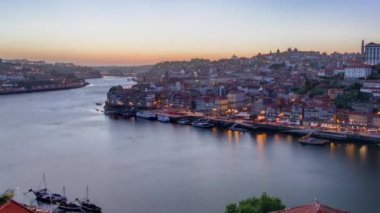 Panorama old city Porto at river Duoro, with Port transporting boats day to night transition timelapse with the Arrabida bridge after sunset, Oporto, Portugal