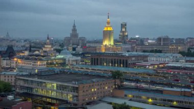 Moskova, Rusya 'daki Komsomolskaya meydanındaki üç tren istasyonunun gece gündüz geçiş zamanlarının en iyi görüntüsü. Trenler raylarda. Arka planda Stalin gökdelenleri var. Çatıdan hava görüntüsü