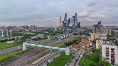 Moskova gökdelenlerinin iş kompleksi hava panorama günden geceye geçiş zamanı. Ön planda demiryolu ve otomobil üst geçidi. Bulutlu gökyüzü ve gün batımından sonra çatıdan gelen trafik