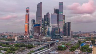 Moskova 'daki gökdelenlerin iş kompleksi hava gününden geceye geçiş zamanını kapatıyor. Ön planda demiryolu ve otomobil üst geçidi. Bulutlu gökyüzü ve gün batımından sonra çatıdan gelen trafik