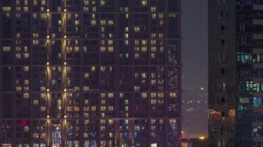Şehrin hava akımının yerleşim bölgesinde parlayan pencereleri olan uzun apartman blokları. Büyük kulelerdeki ve gökdelenlerdeki odalarda akşam ışığı