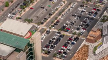 Otoparka park edilmiş rengarenk arabaların hava manzarası park yerleri için çizgiler ve işaretler ve tüm gün boyunca yol tarifleri. Uzun gölgeler hızlı hareket ediyor. Dubai Finans Merkezi